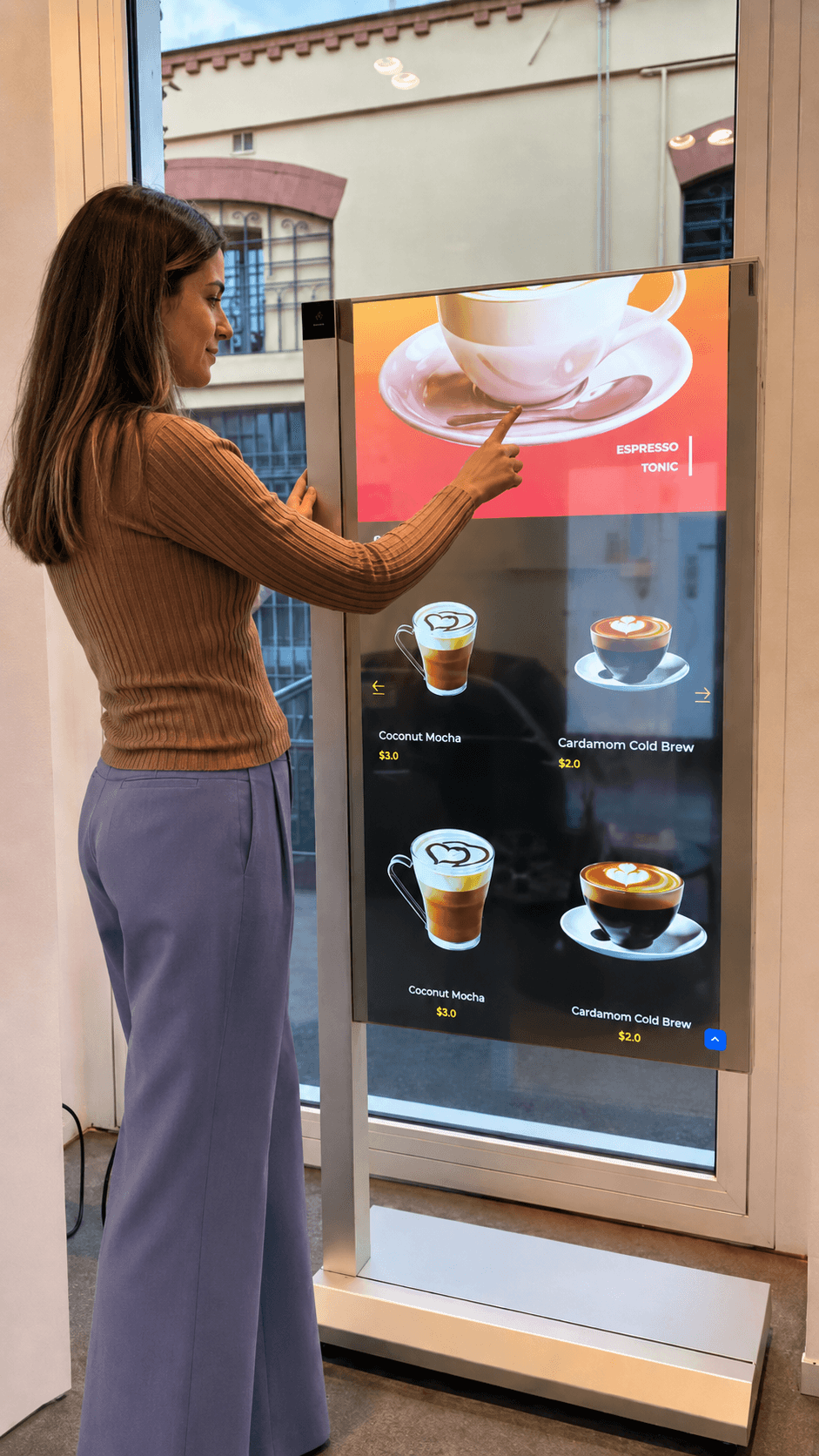 Mulher interage com um quiosque digital vertical exibindo diferentes tipos de café e preços.